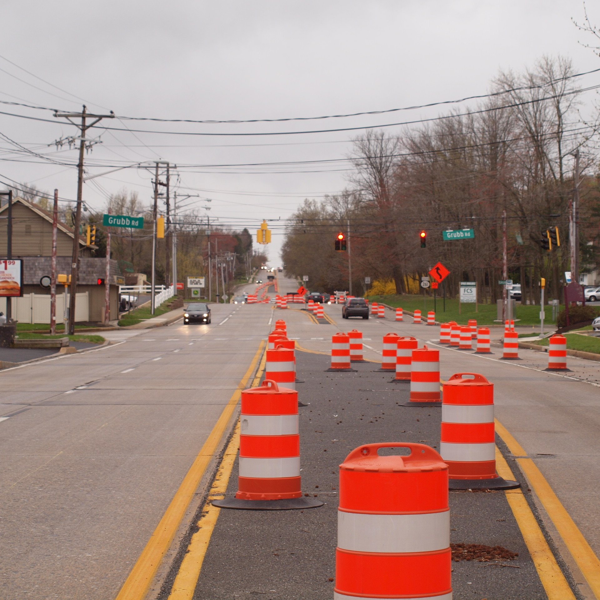 Orange Traffic Barrels Lining a Suburban Road with Traffic Flow