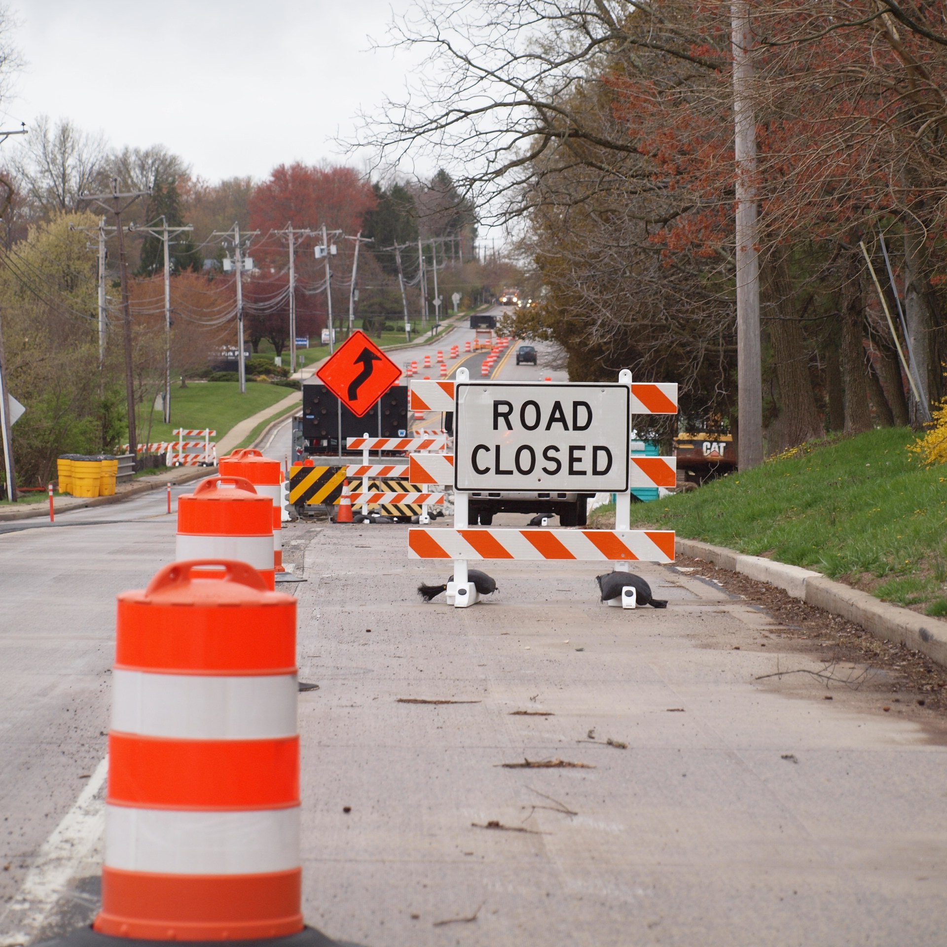 Lane closure with road closed sign, traffic barrels, and safety barricades on a suburban street
